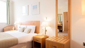 Ein Hotelzimmer mit Bett, Nachttischen, einem Spiegel und einem fenster mit Vorhängen.