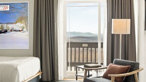 A hotel room with a bed, a chair, a table, and a view of mountains through a large window. - Sun Lodge near Manchester VT, Ascend Collection Hotel (Peru)