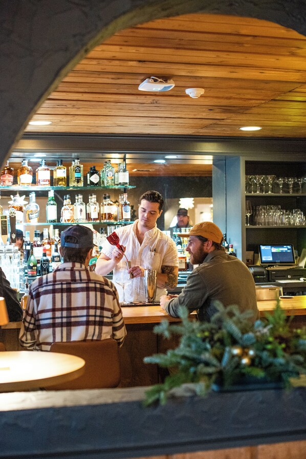 Uma área de bar com teto de madeira, prateleiras com garrafas e balcão.