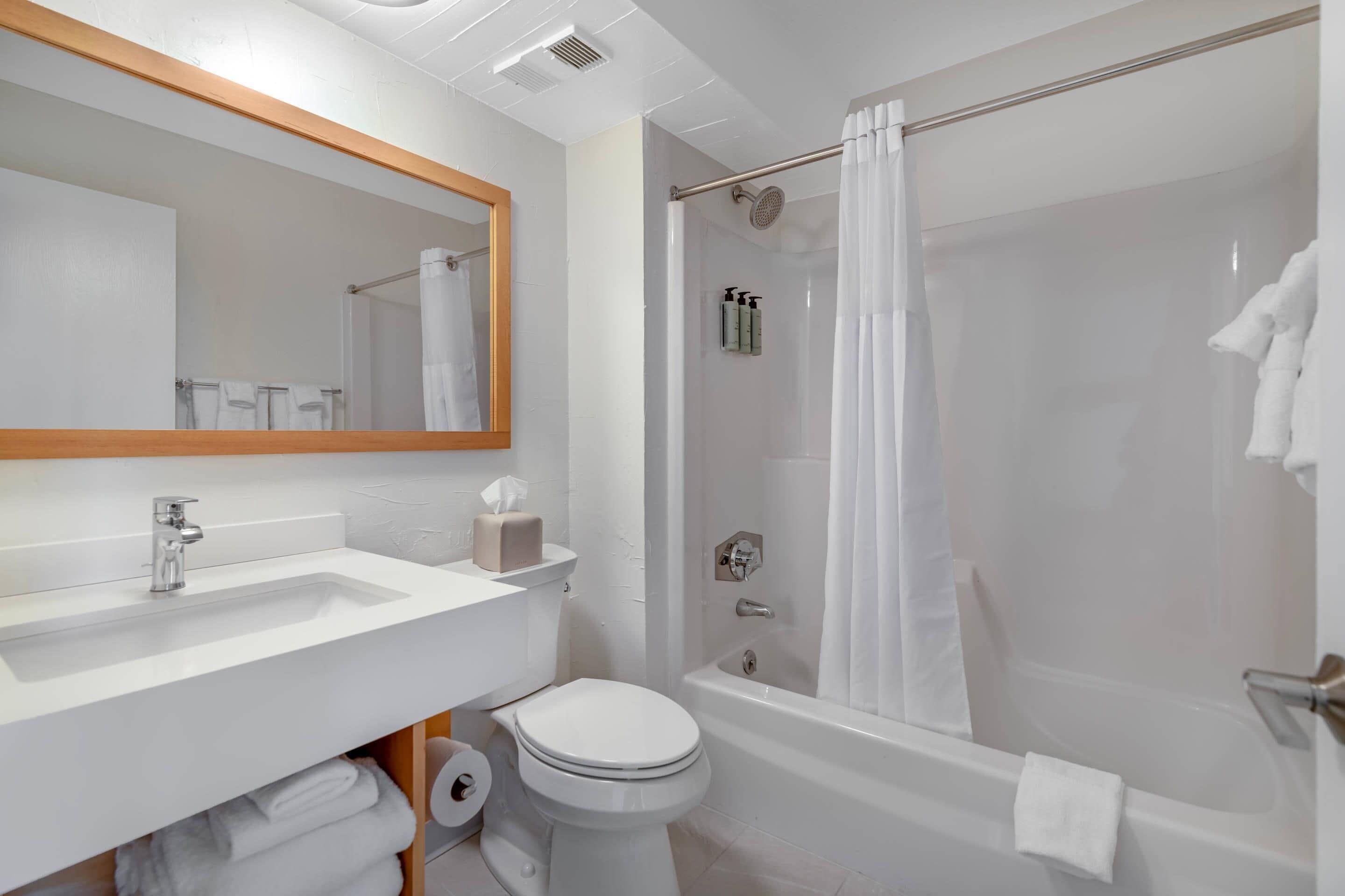 Een moderne badkamer met een witte wastafel, toilet en badkuip.