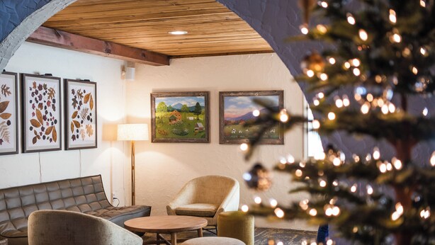 A cozy room with a sofa, armchair, and round table, decorated with leaf-patterned artwork and a lamp. - Sun Lodge near Manchester VT, Ascend Collection Hotel (Peru)
