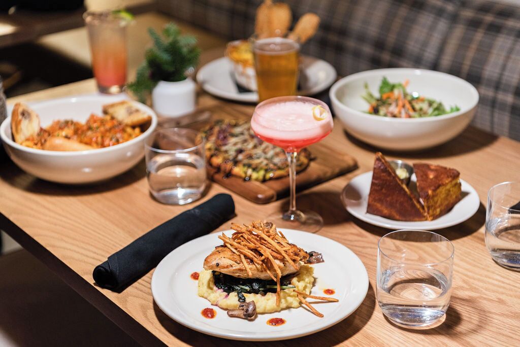 Una mesa de comedor con varios platos, incluyendo un sándwich, una ensalada y un postre.