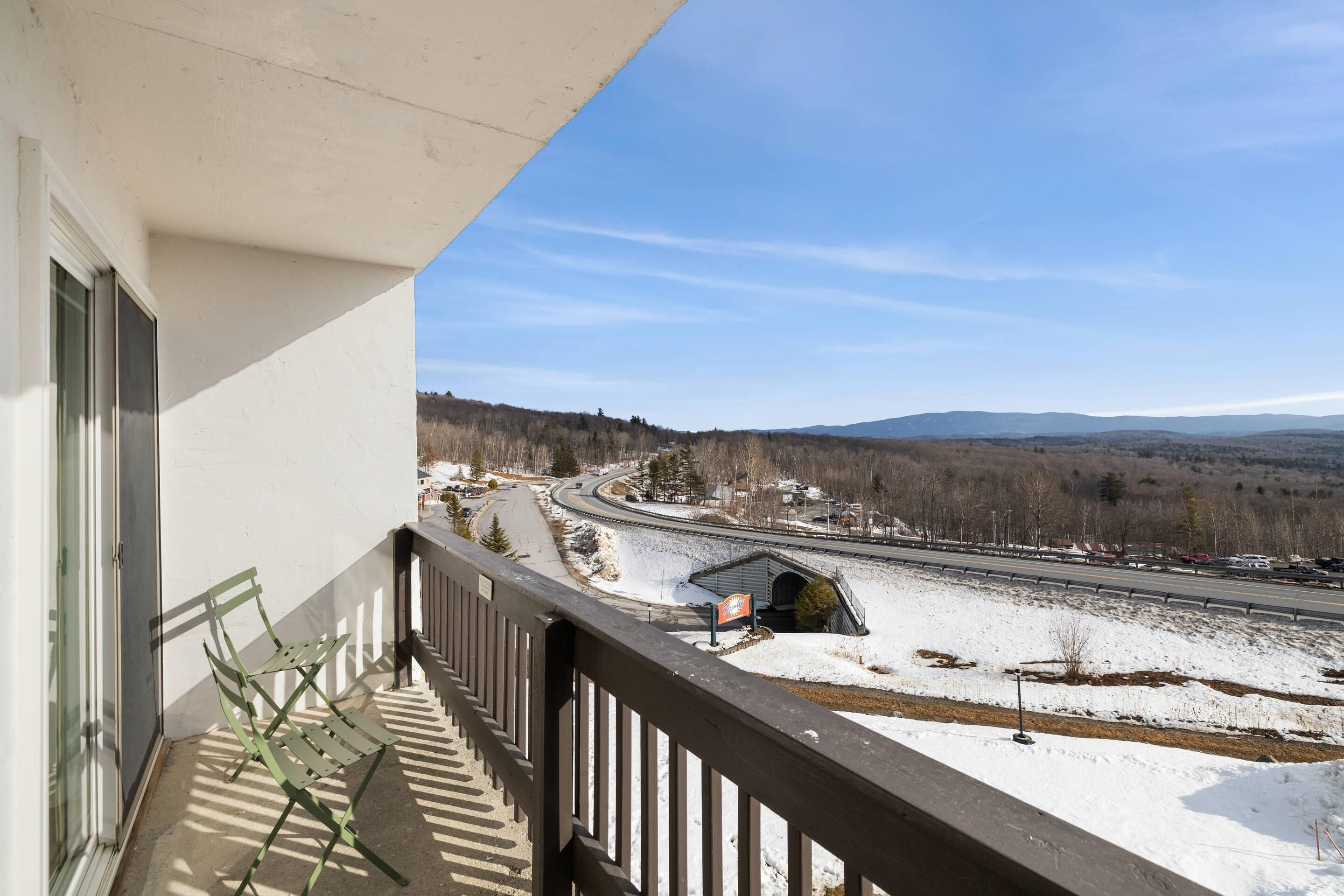 A balcony with a view of a snow-covered landscape and a highway.