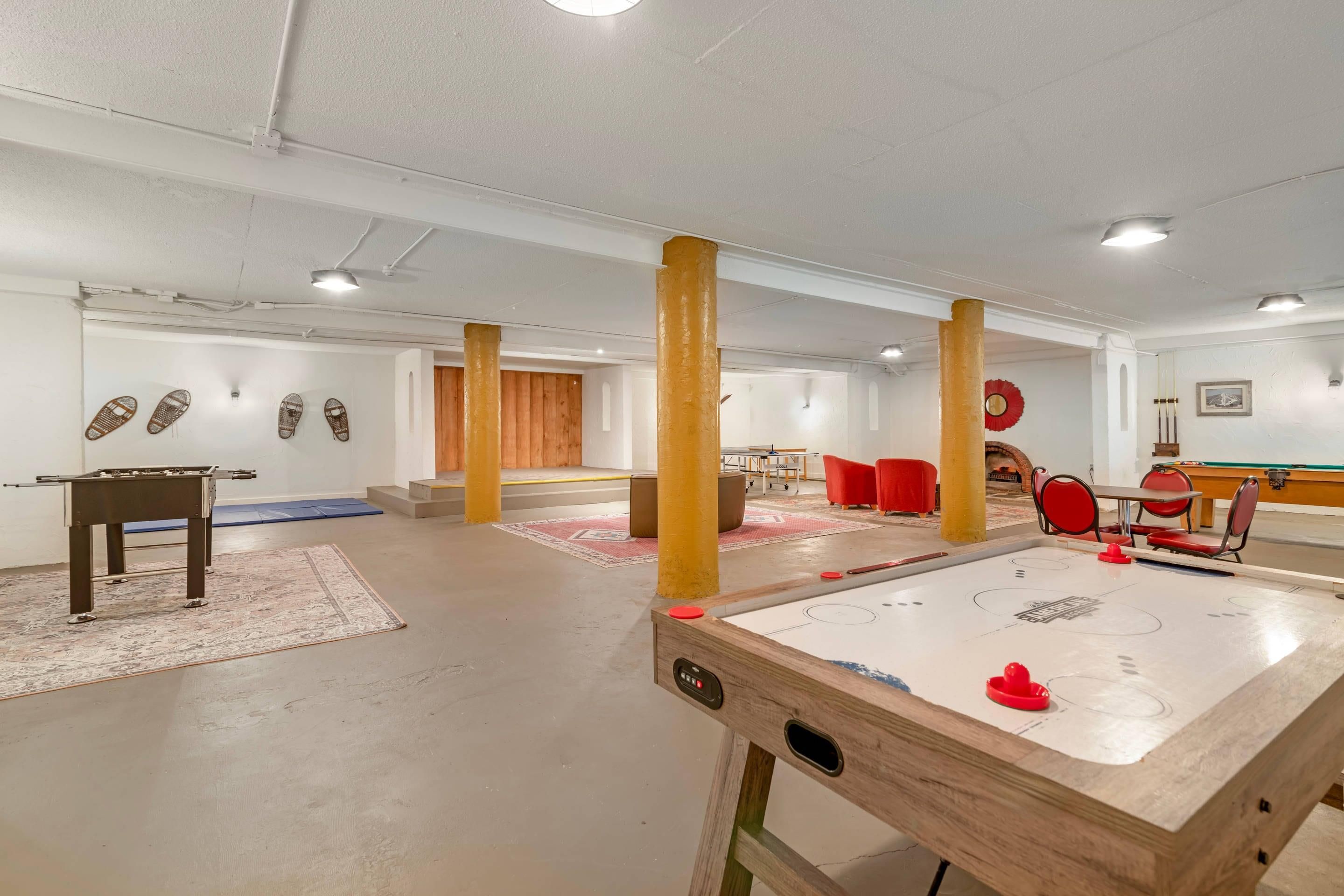 A room with a foosball table, a pool table, and red chairs.