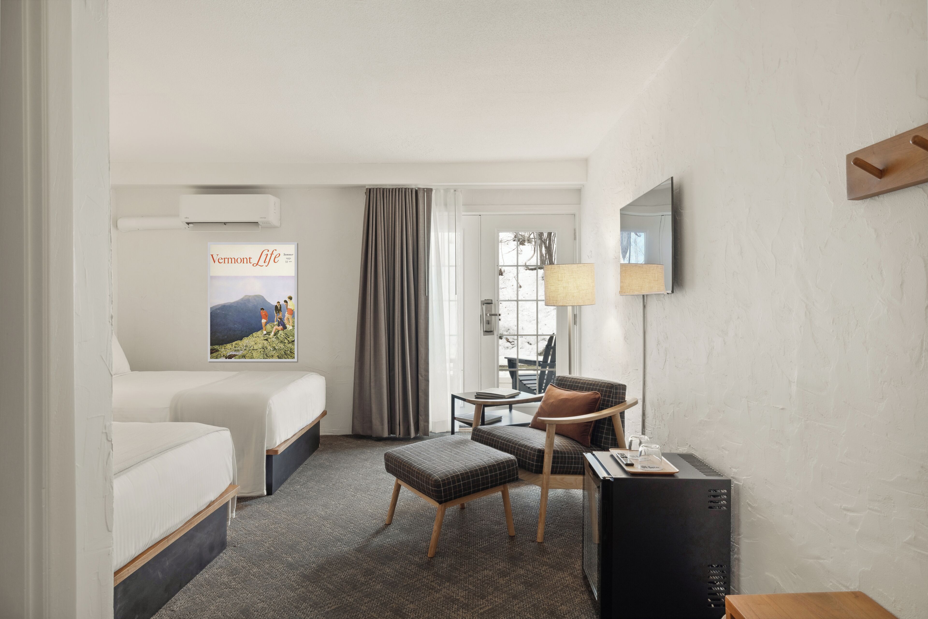 Ein Hotelzimmer mit Bett, Schreibtisch mit Stuhl, Fernseher und einem Bild an der Wand.