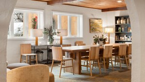 A dining area with a wooden table and chairs, a window with a view, and a bookshelf with books and decorative items. - Sun Lodge near Manchester VT, Ascend Collection Hotel (Peru)