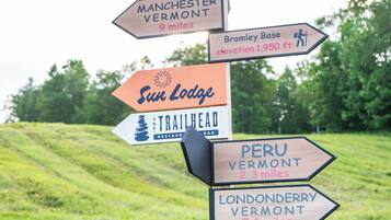 A directional signpost with multiple destinations including Manchester Vermont, Hapagood Pond Recreation Area, Bromley Base, Sun Lodge, Trailhead, Peru Vermont, and Londonderry Vermont.
