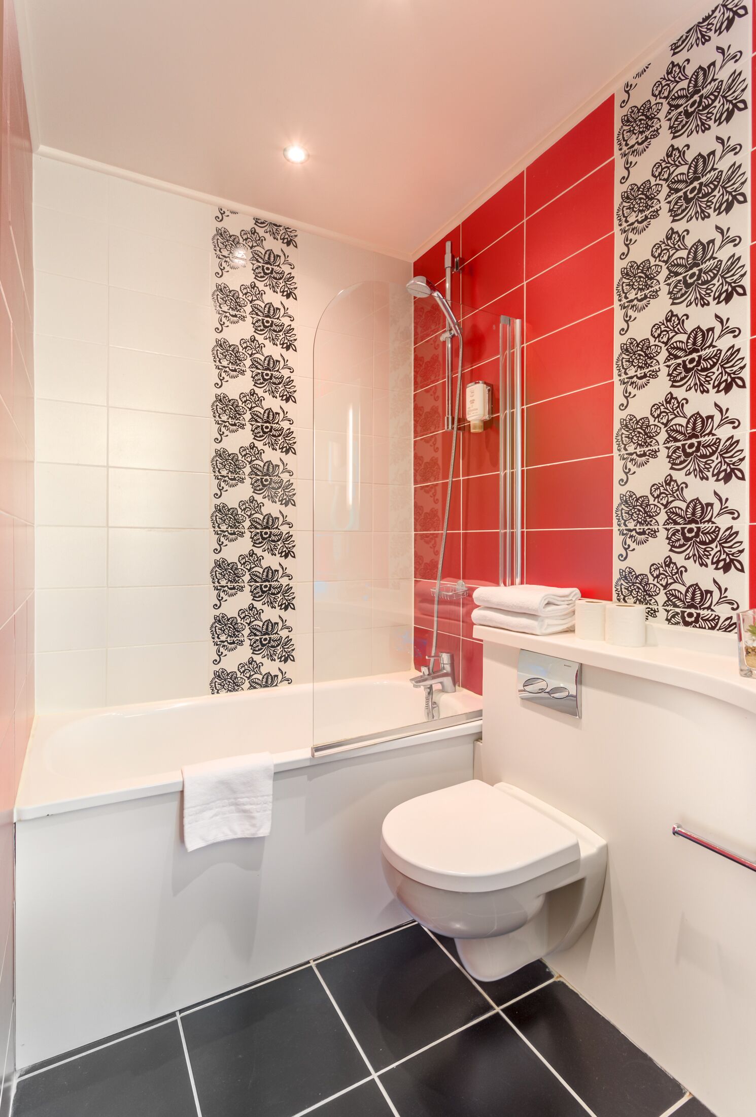 A bathroom with a white bathtub, a white toilet, and a shower area.