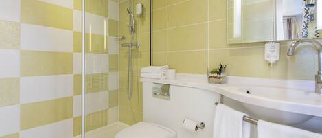 A bathroom with a shower, toilet, sink, and a mirror.