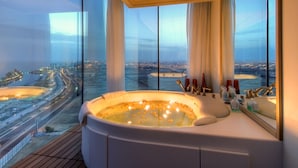 Een luxe badkamer met een groot bad, een spiegel en uitzicht op een stadsgezicht.