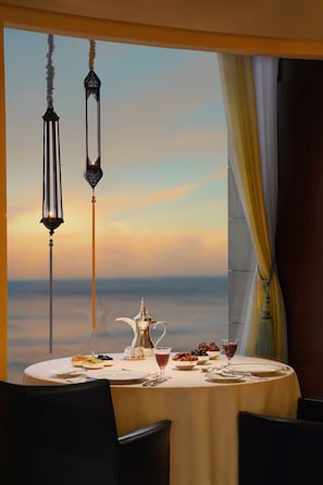 A dining table set for two with a view of the sea at sunset. - Rosewood Jeddah (Jeddah)