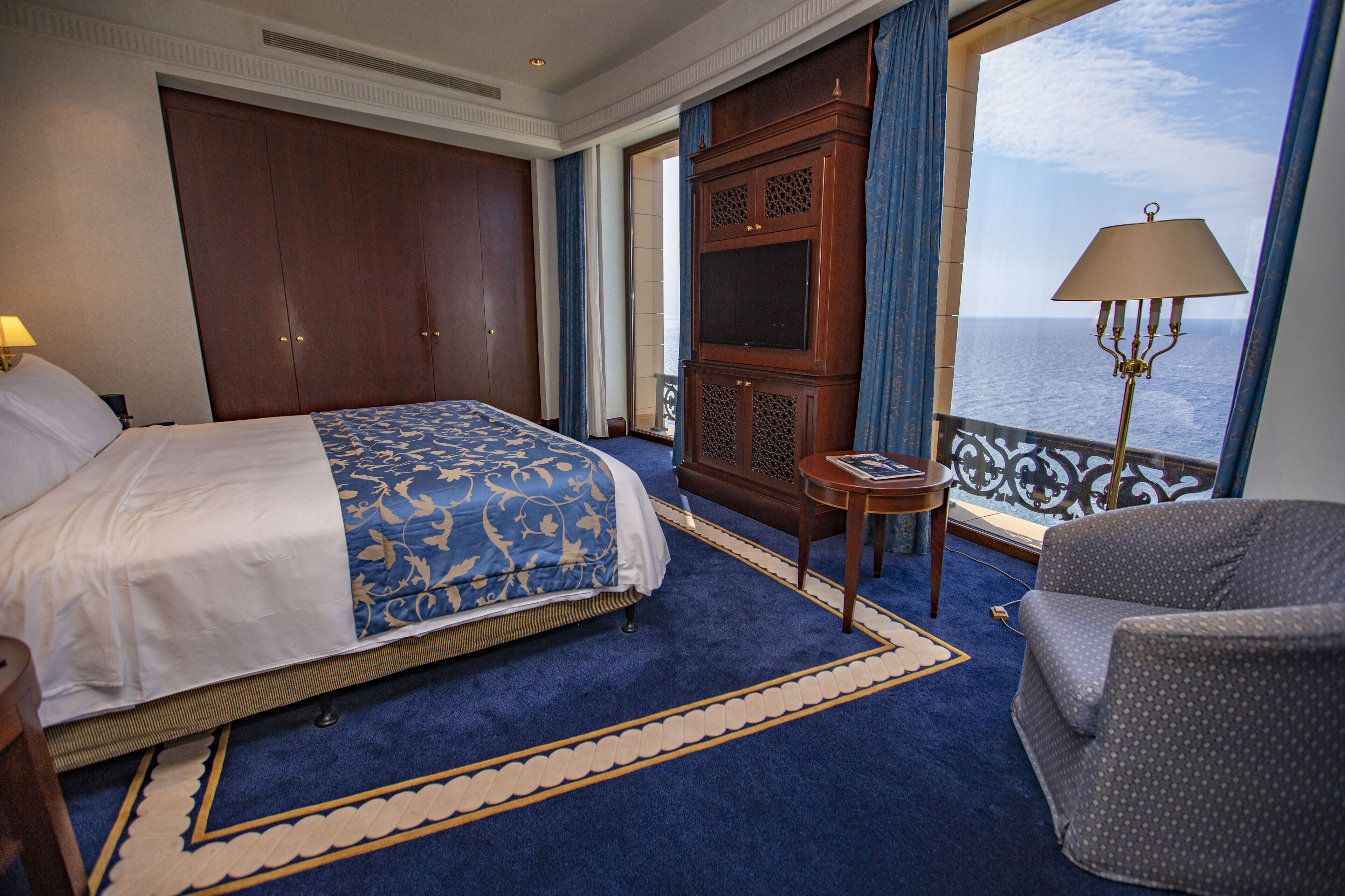 Habitación de hotel con una cama grande, una mesita, una silla, un armario y vista al mar.