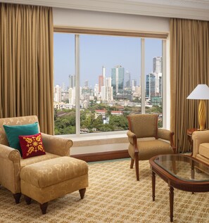 A hotel room with a large window offering a cityscape view. There are two armchairs and a small table. - ITC Grand Central, a Luxury Collection Hotel, Mumbai (Mumbai)