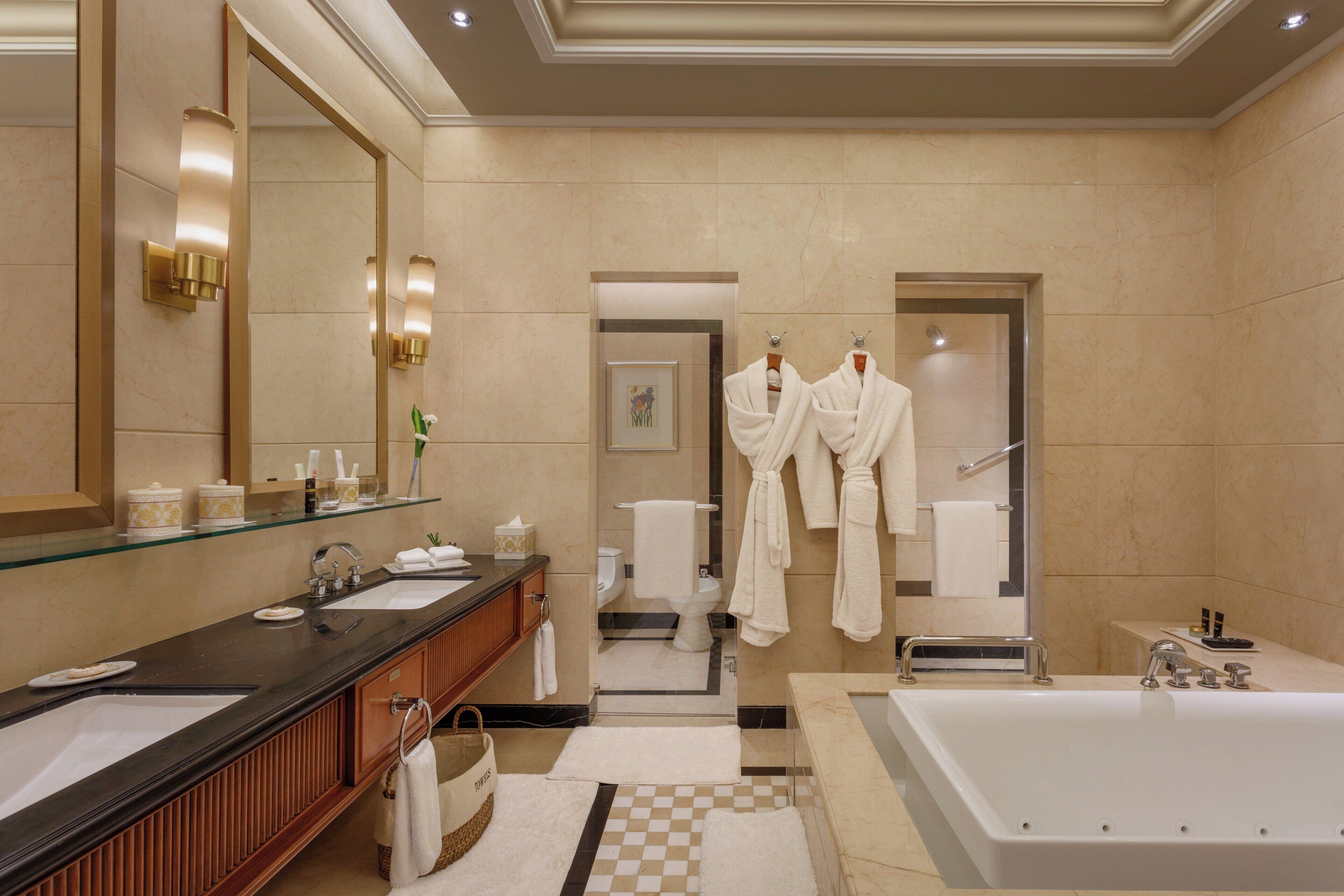 A modern bathroom with a large mirror, two sinks, a bathtub, and a shower area.
