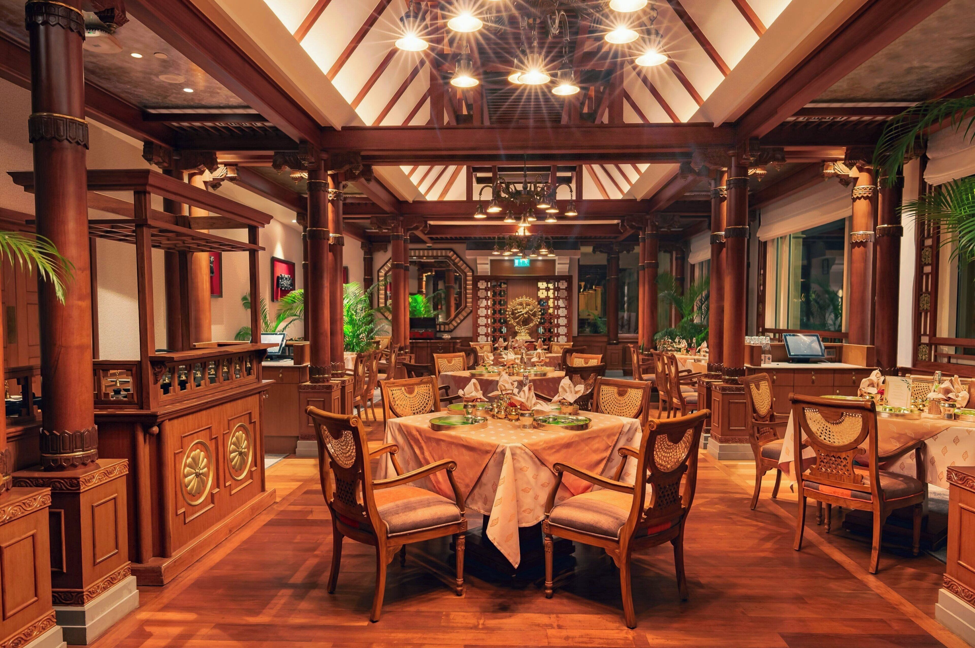 A traditional dining area with wooden furniture, a central table set for a meal, and a ceiling with exposed beams and lighting fixtures.
