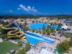 Un resort con una piscina grande, toboganes acuáticos y una zona de playa.