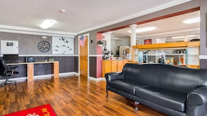 A hotel lobby with a wooden desk, black leather sofa, and a red carpet with text. - Econo Lodge Jacksonville near Little Rock Air Force Base (Jacksonville)