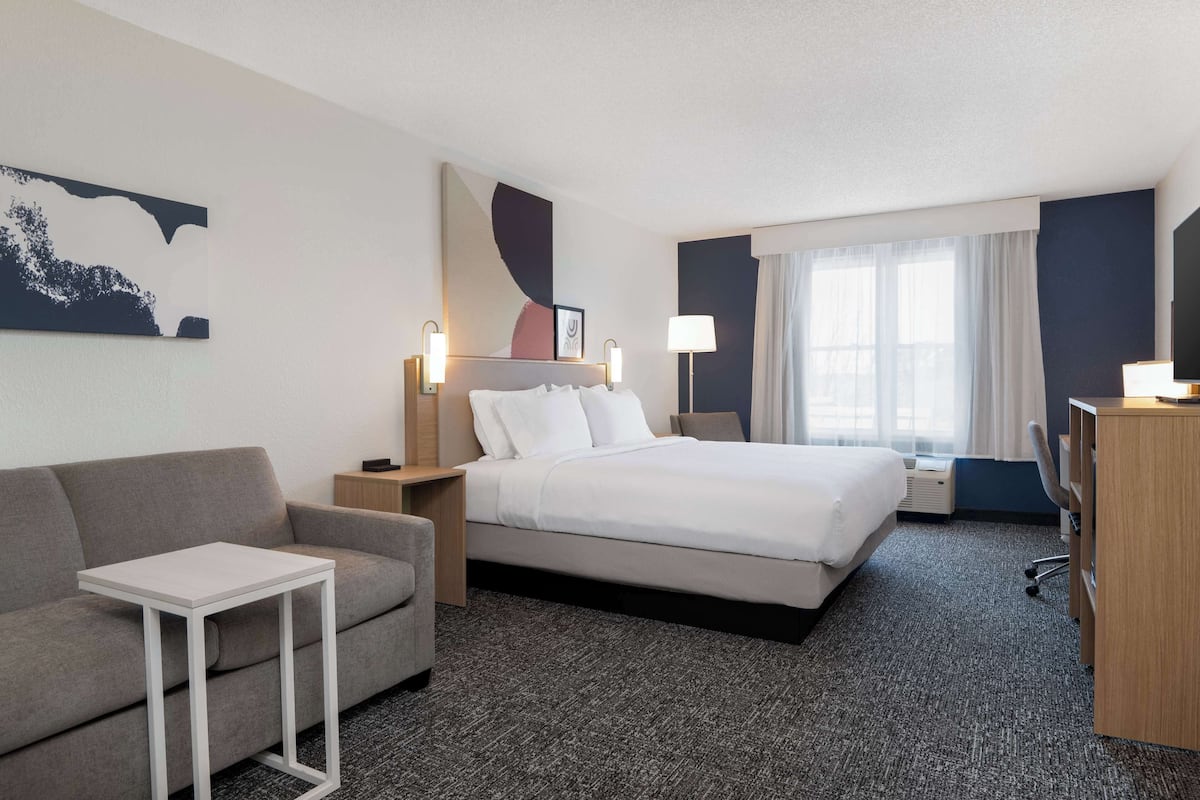Een hotelkamer met een bed, een bank, een klein tafeltje, een bureau en een lamp.