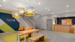 Un área de recepción moderna con un mostrador de madera, una escalera y una zona de estar con una mesa y bancos.