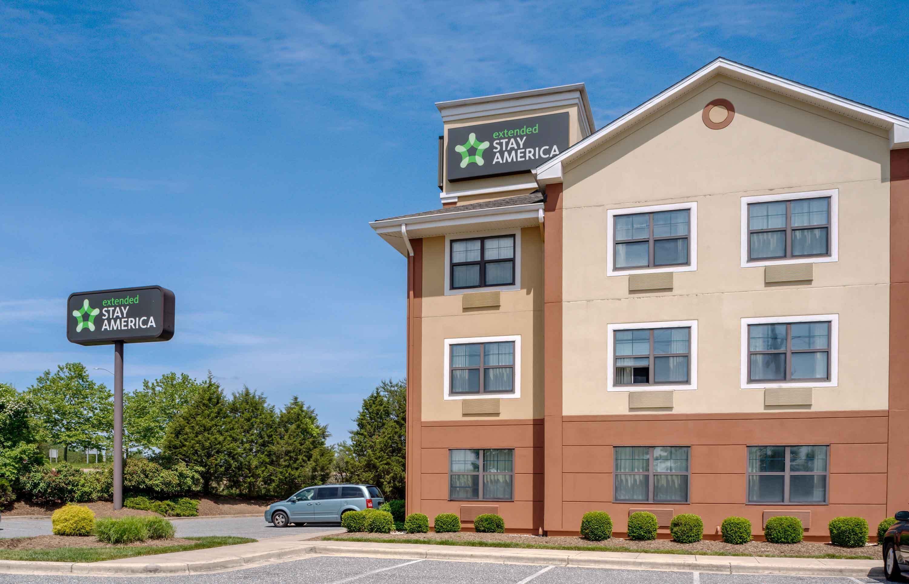 A Stay America hotel with a modern facade, multiple windows, and a parking lot.