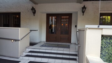 Un ingresso principale con una doppia porta, una scalinata che vi conduce e due lanterne a parete.