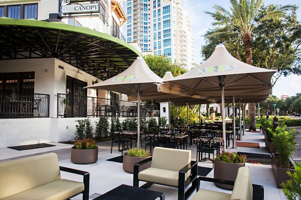 An outdoor seating area with tables and chairs, umbrellas, and planters.
