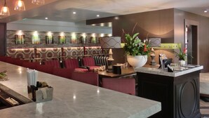 Un restaurante moderno con una barra alargada, asientos rojos e iluminación colgante.