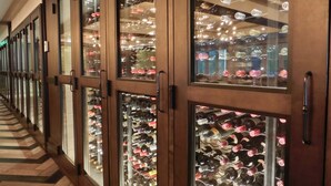 Un pasillo con vitrinas de vidrio repletas de botellas de vino.