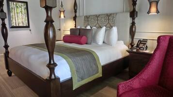 Una cama con dosel, un tablero de noche con un teléfono y una silla roja.