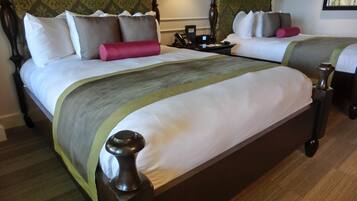 A double bed with a wooden headboard and footboard, a bedside table with a telephone, and a nightstand with a lamp.