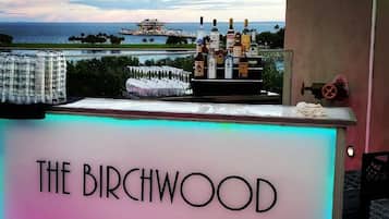 A bar named "The Birchwood" with a view of the ocean and a building in the background.