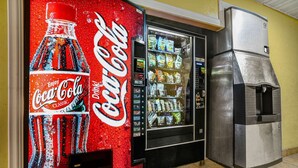 Ein Getränkeautomat mit Coca-Cola-Werbung, ein Getränkespender und ein Kühlschrank.