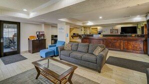 Ein großzügiger Wohnbereich mit einer Couch, Sesseln, einem Couchtisch sowie einer Küchenzeile mit Arbeitsfläche und Geräten.