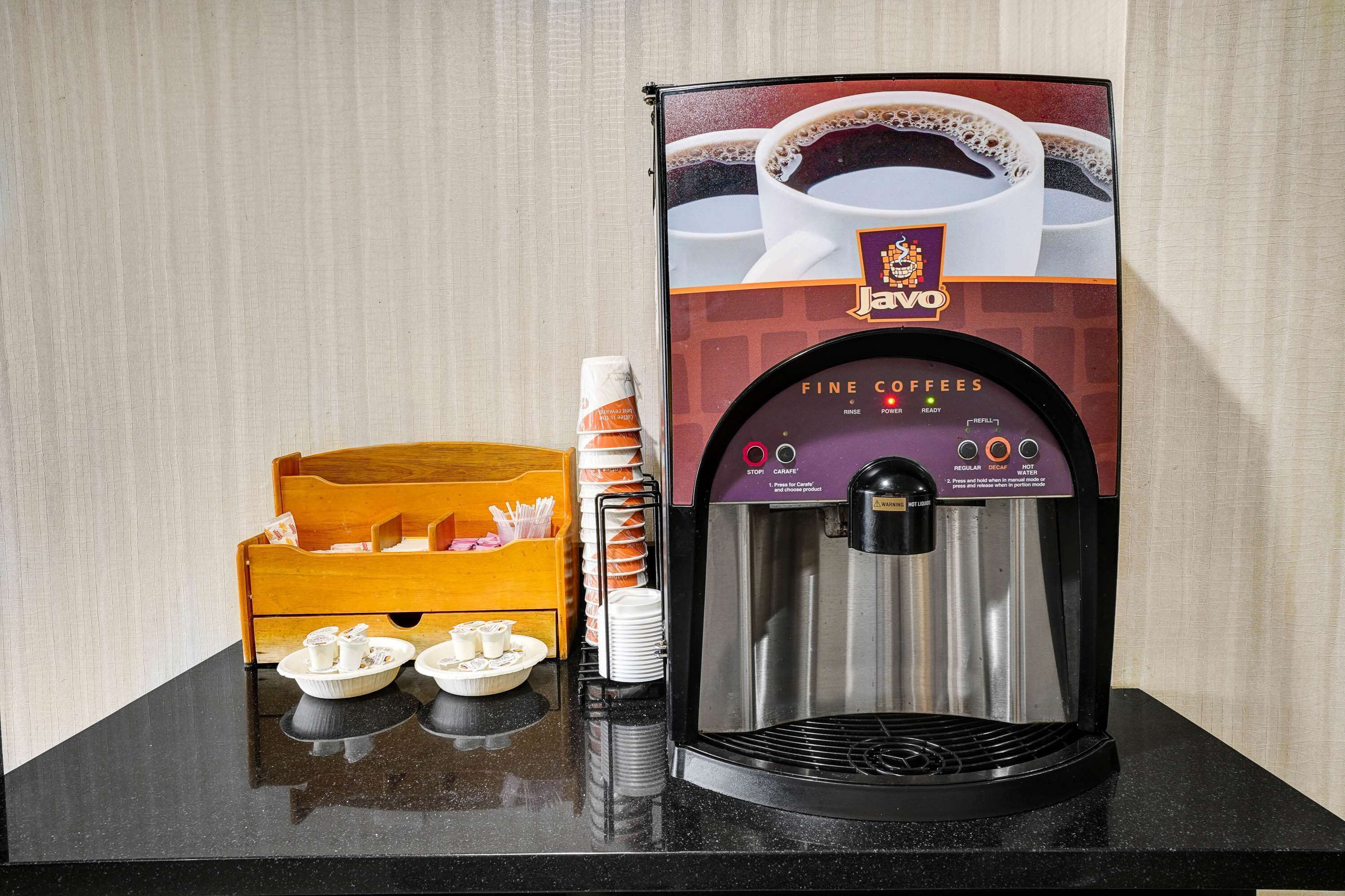 Een koffieapparaat met een beker met branding en een bak wegwerpbekers.