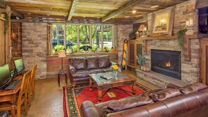 A cozy living room with a stone fireplace, leather sofas, and a stone wall. - Annabelle Inn (Aspen)