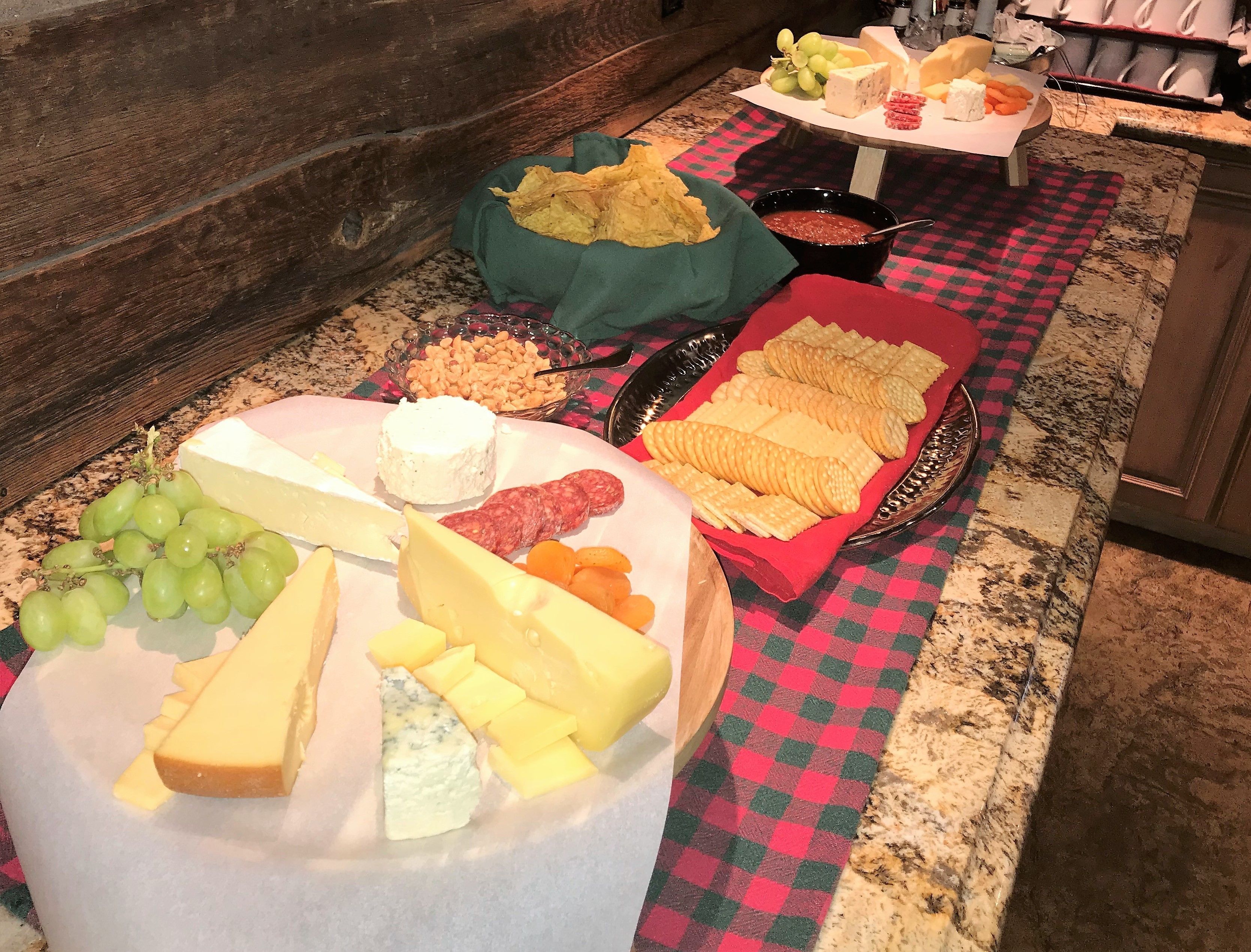 Tabla de quesos y embutidos con diversos quesos, galletas y frutas.