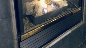 A fireplace with burning logs and a metal grate.