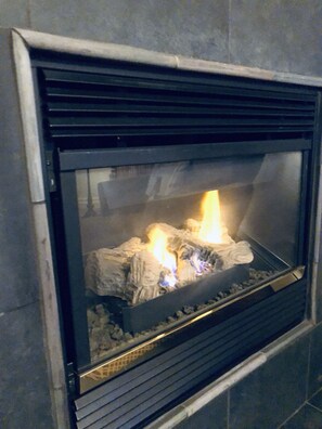A fireplace with burning logs and a metal grate.