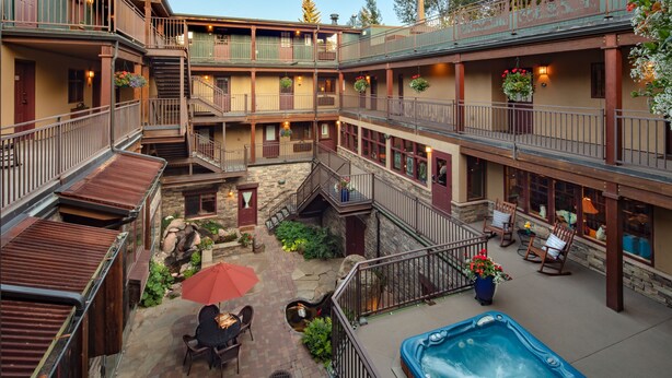 A multi-level courtyard with outdoor seating, a hot tub, and a stone fountain. - Annabelle Inn (Aspen)