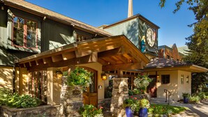 A two-story house with a stone chimney, a wooden porch, and a clock on the second floor. - Annabelle Inn (Aspen)