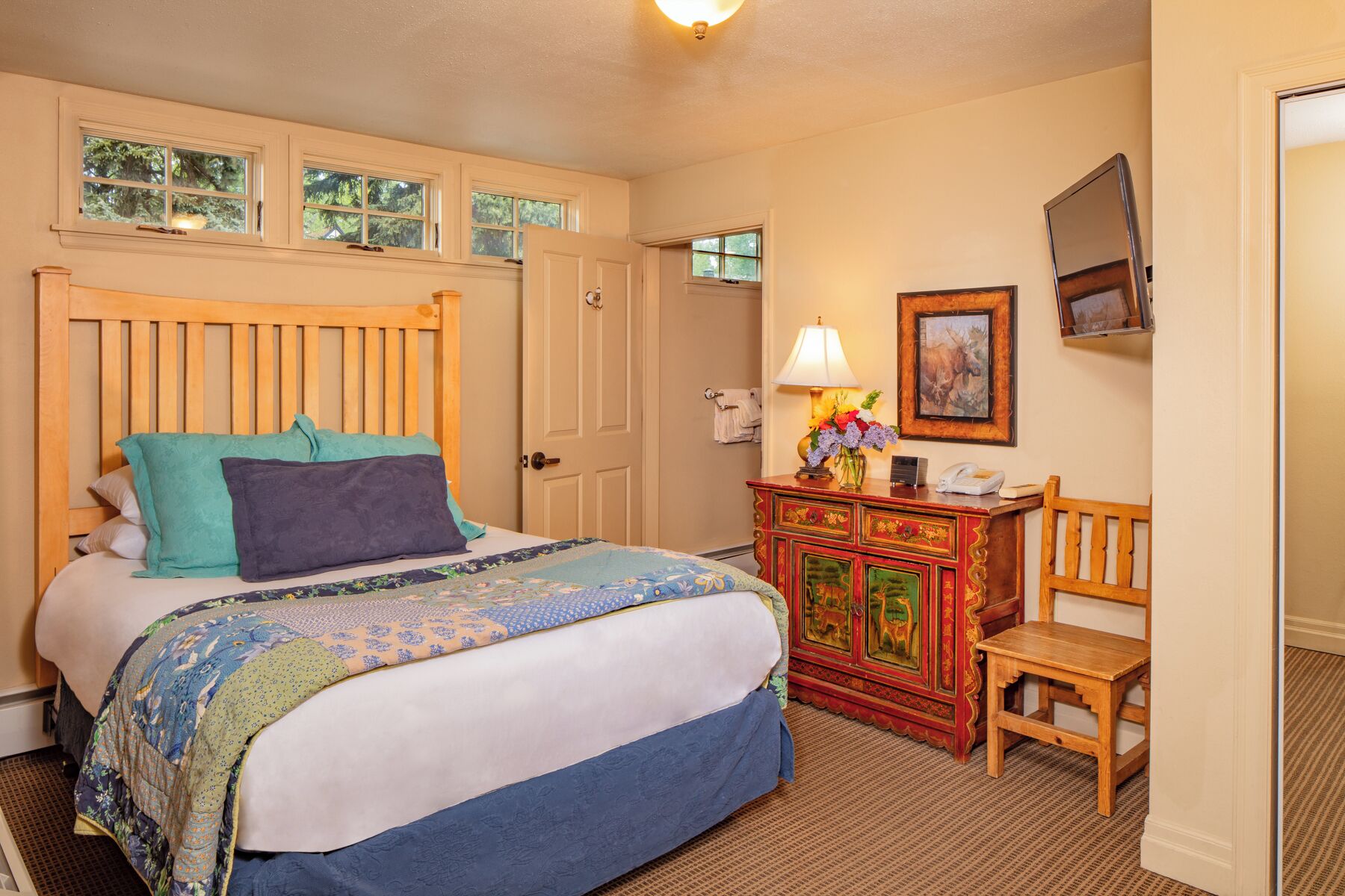 A bedroom with a wooden bed, a dresser with a mirror, and a door.