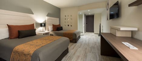 A hotel room with two beds, a desk, a TV, and a bathroom visible through an open door.