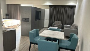 A modern hotel room with a bed, a desk, a seating area with chairs, a small table, and a TV. - Real Inn San Luis Potosí (San Luis Potosi)
