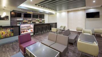 A modern lounge area with seating, a bar, and a refrigerated display.