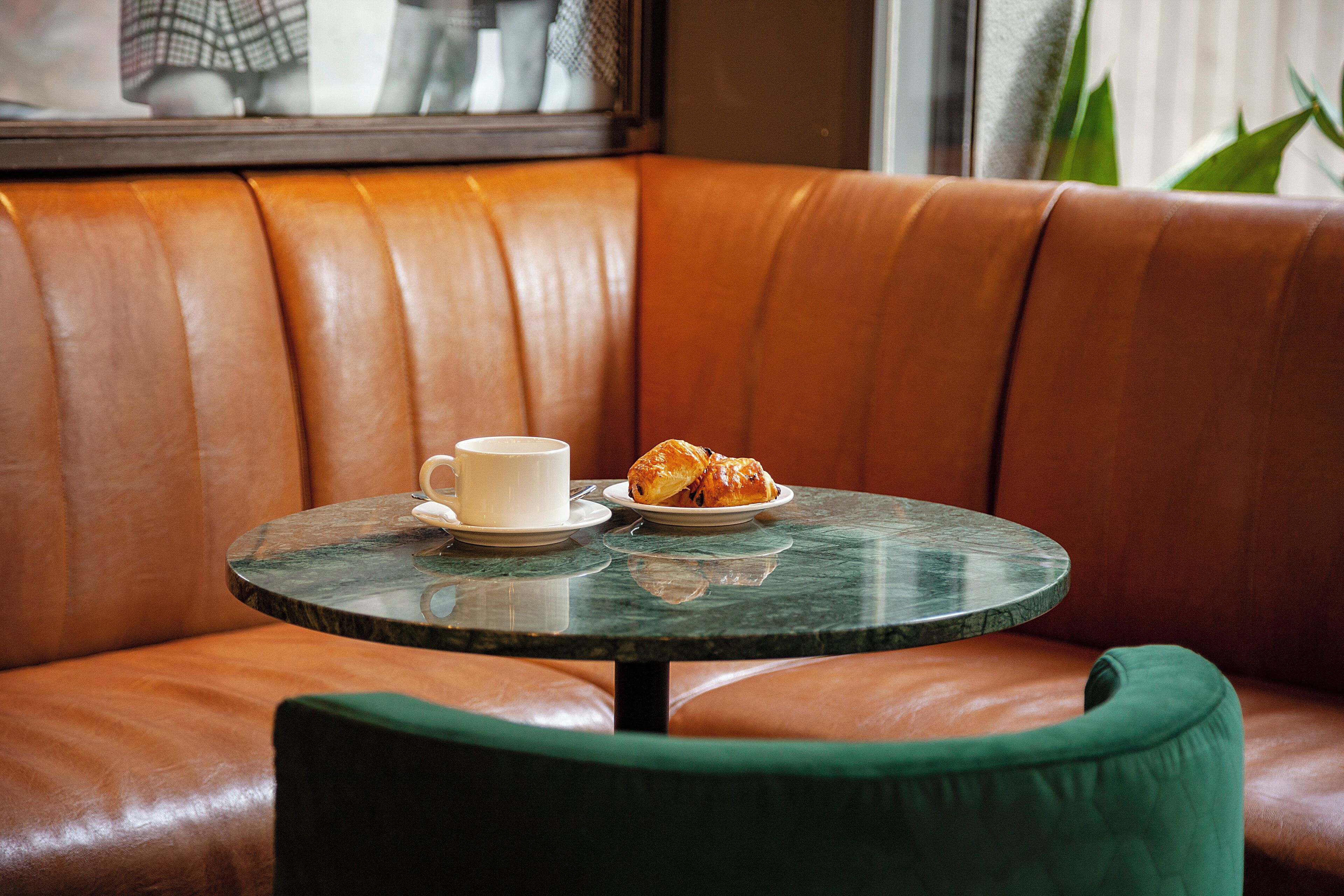 Un sofá de cuero con una mesa redonda y una silla verde.