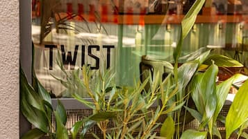 A window with the text "TWIST RESTAUNT" and green plants in front.