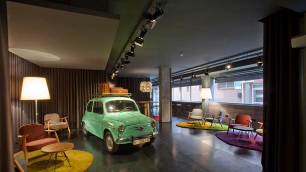 A modern interior with a vintage car, contemporary furniture, and a large window providing natural light.