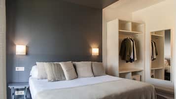 Moderni hotellihuone, jossa on suuri sänky, yöpöydällä olevat lamput, vaatekaappi ja peili.