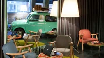 Un interior moderno con un coche antiguo verde al fondo, una mesa de centro redonda y dos sillones.
