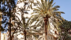 A multi-story building with balconies, surrounded by palm trees. - Sixties Ramblas (Barcelona)